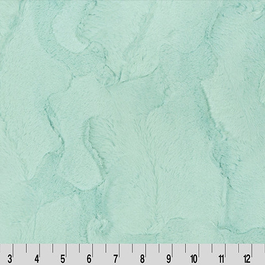 Textured green fabric with a ruler at the bottom for scale