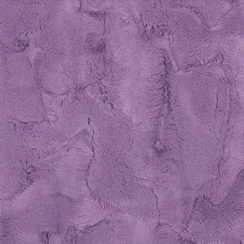 A close-up of a purple faux fur or plush fabric texture with a ruler scale at the bottom indicating measurements.