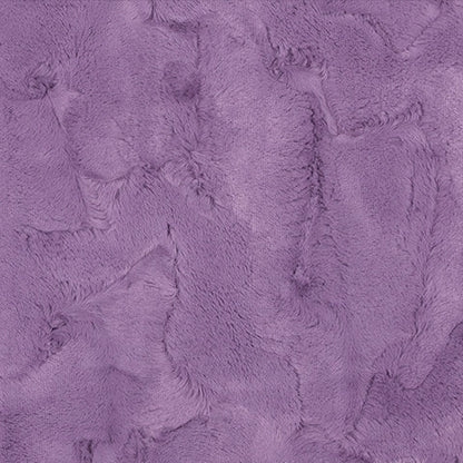 A close-up of a purple faux fur or plush fabric texture with a ruler scale at the bottom indicating measurements.